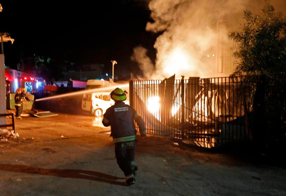  Israeli security forces and firefighters gather near a building set ablaze after it was hit by a rocket fired from the Gaza Strip