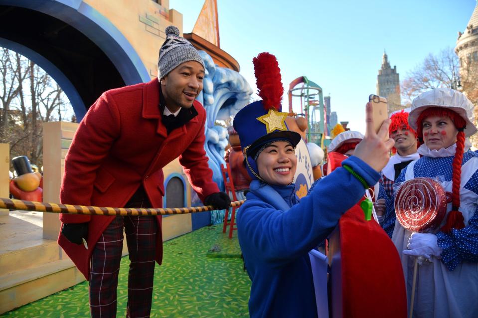  John Legend looked festive in tartan trews as he took a selfie with one of the parade's many performers