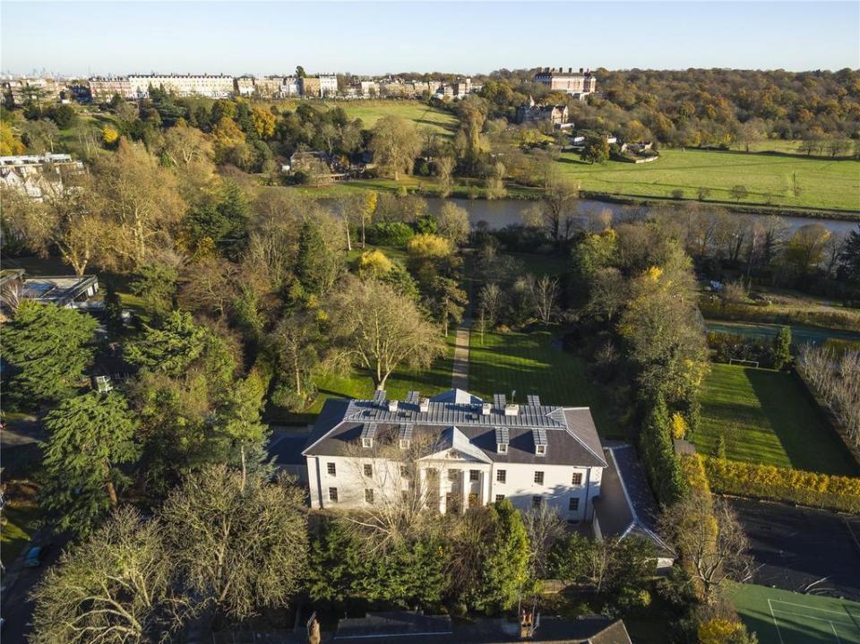  The huge house is surrounded by trees and faces a lake