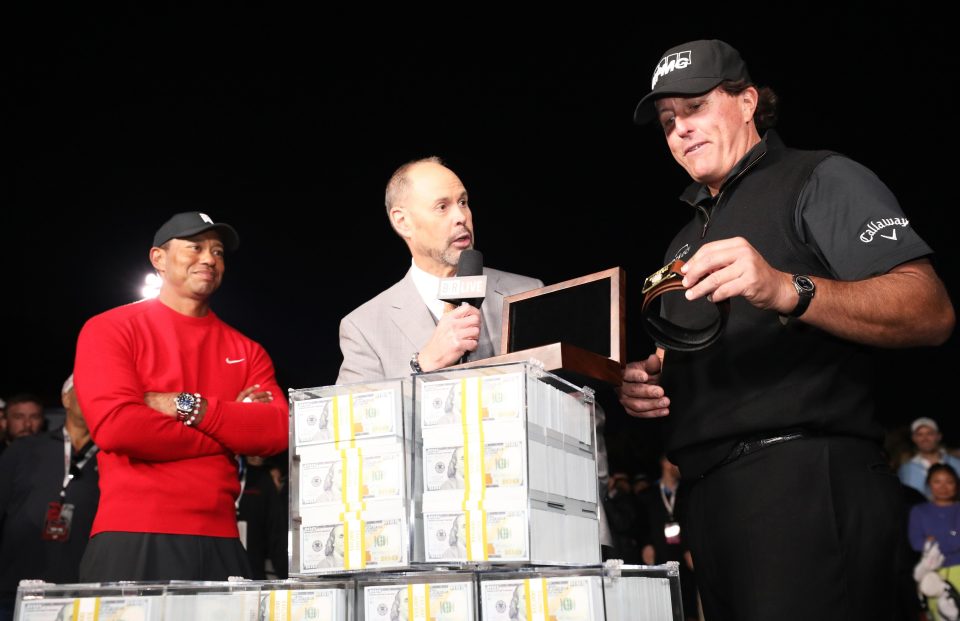 Phil Mickelson celebrates with the winnings after defeating Tiger Woods