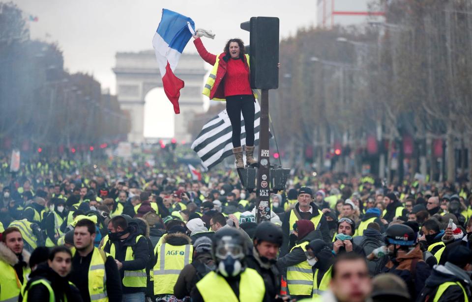  A protester waves a tricolour from a traffic light as violence erupts on the streets