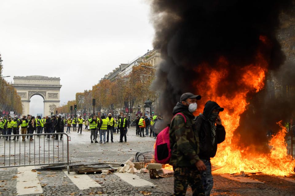  Protesters stands in front of a fire during a protest in Paris