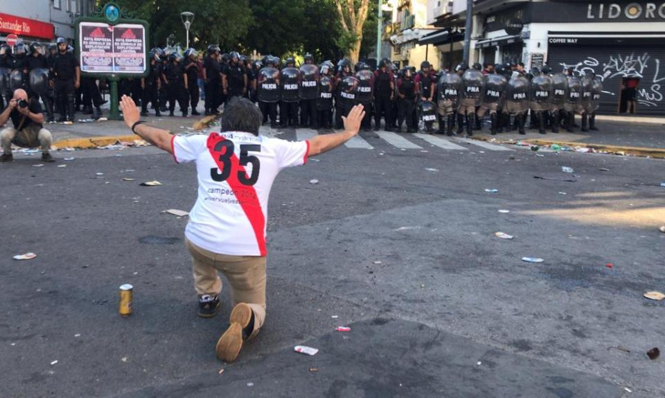 A River Plate fan holds his hands up in front of police