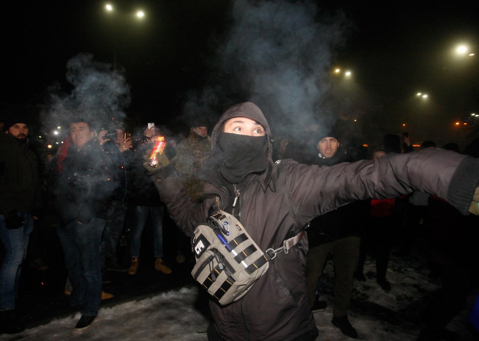 A protester prepares to hurl a smoke grenade outside the Russian embassy in Kiev