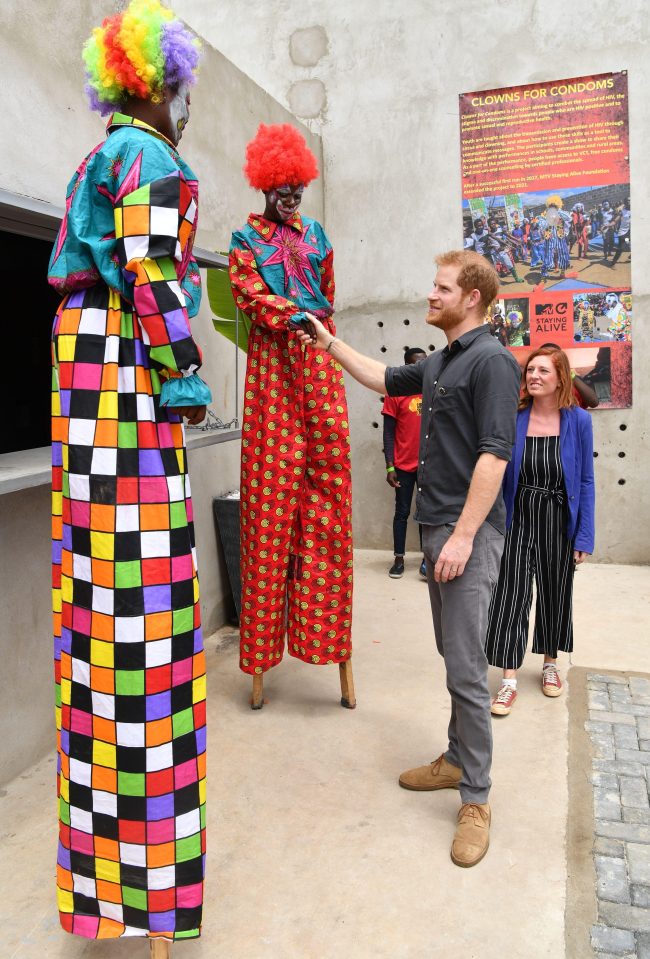  Tall order, as Prince Harry stretches to shake hands with some of the performers on stilts