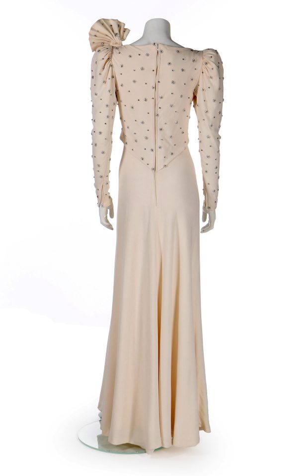  The long-sleeved, full-length gown has a large bow behind the left shoulder