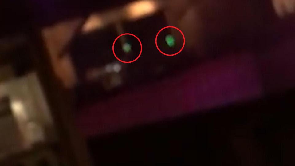  What appears to be laser lights from a gun scope are seen flashing against the bar's walls