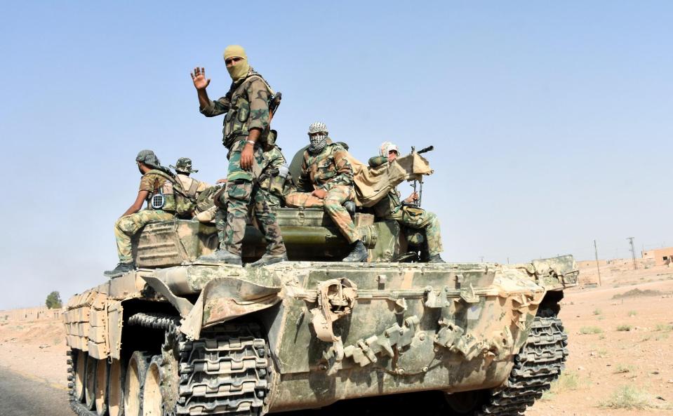  Members of the Syrian government forces ride on a tank, in the village of Kobajjep on the southwestern outskirts of Deir Ezzor province