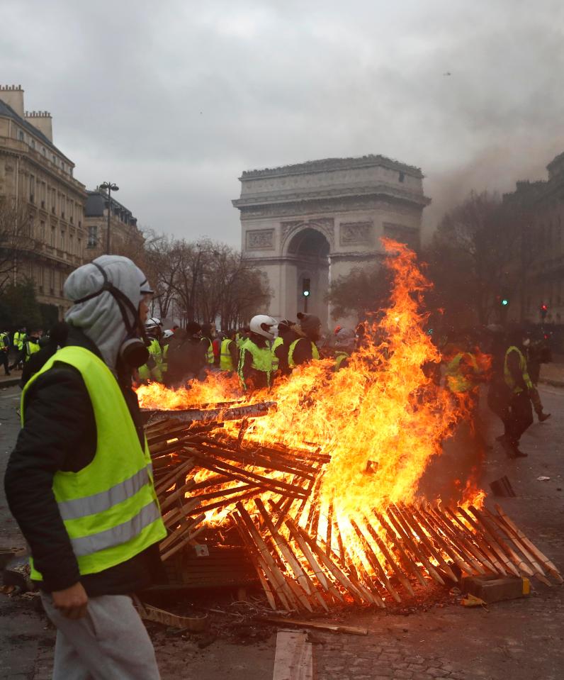  Demonstrators walk by a burning barricade near the Arc de Triomphe