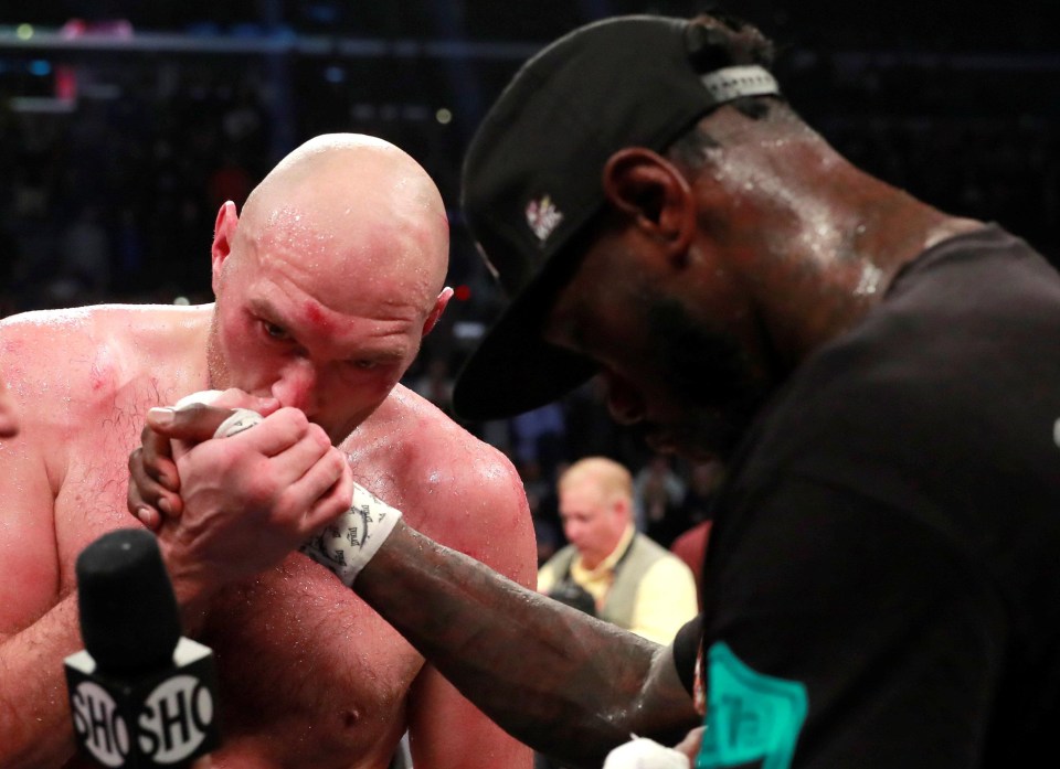 Tyson Fury kisses Deontay Wilder's fist after a hard-fought battle in the ring