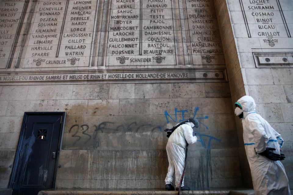  Workers clean up the graffiti scrawled on the Arc de Triomphe