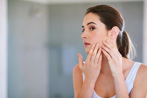 a woman is looking at her face in the mirror