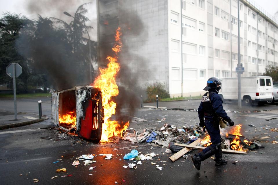  A French riot cop walks past a burning car during a protest in Nantes today