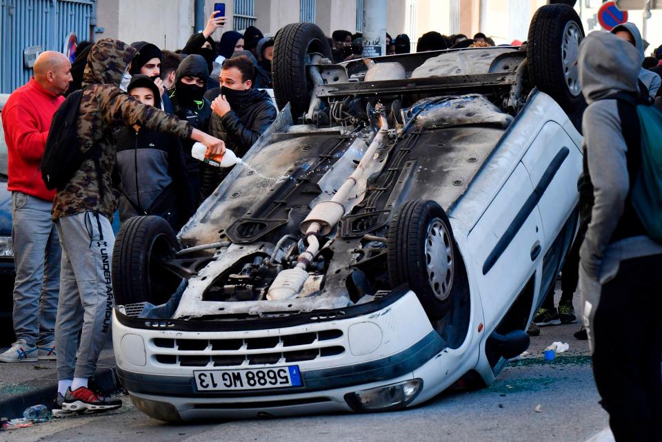  A man pours liquid fuel on an overturned vehicle in Marseille