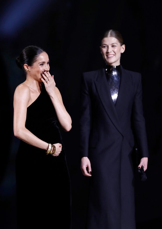  Meghan cradled her bump as she took to the stage to present the British Designer of the Year alongside Rosamund Pike