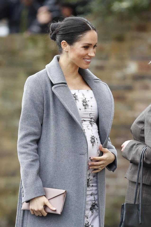 Meghan Markle puts her hand on her growing baby bump