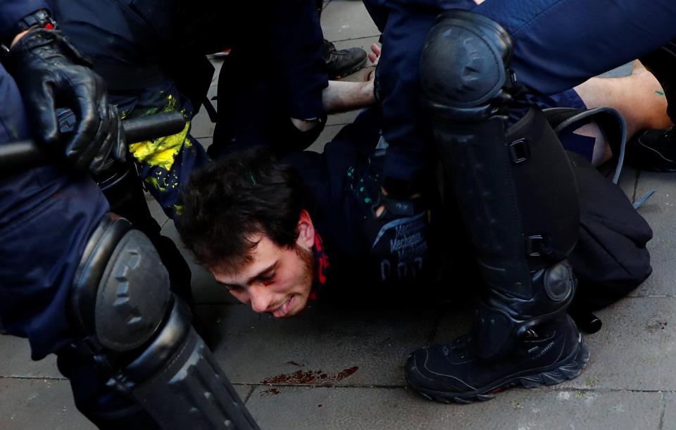  A protester is held to the ground by police as his face bleeds