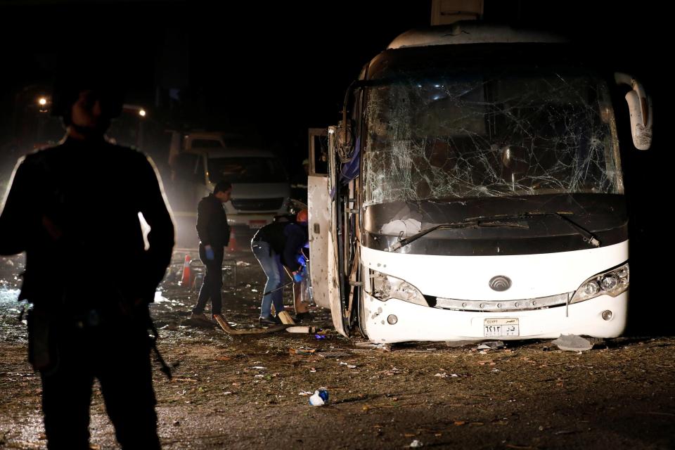 Police officers inspect a scene of a bus blast in Giza, Egypt