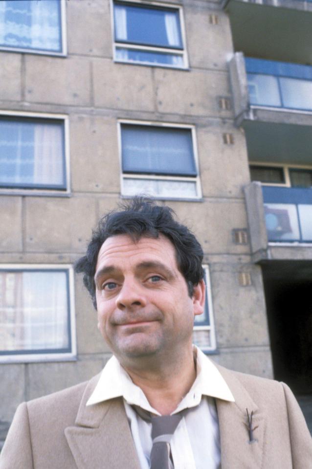  Del Boy standing in front of the tower block in a still from the show