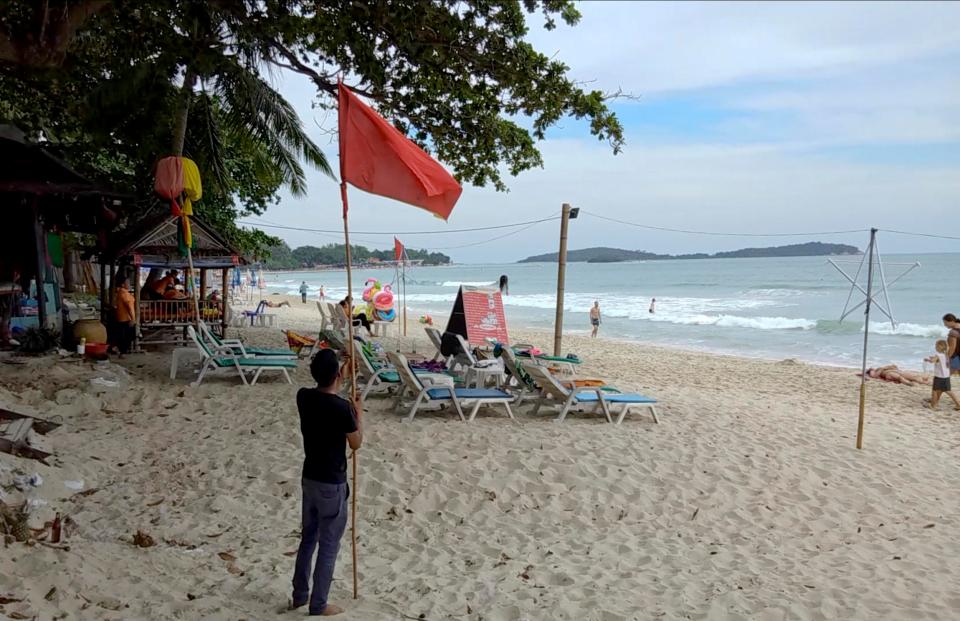  A man raises a red flag indicating rough weather conditions in Chaweng beach, Koh Samui - ahead of storm Pabuk