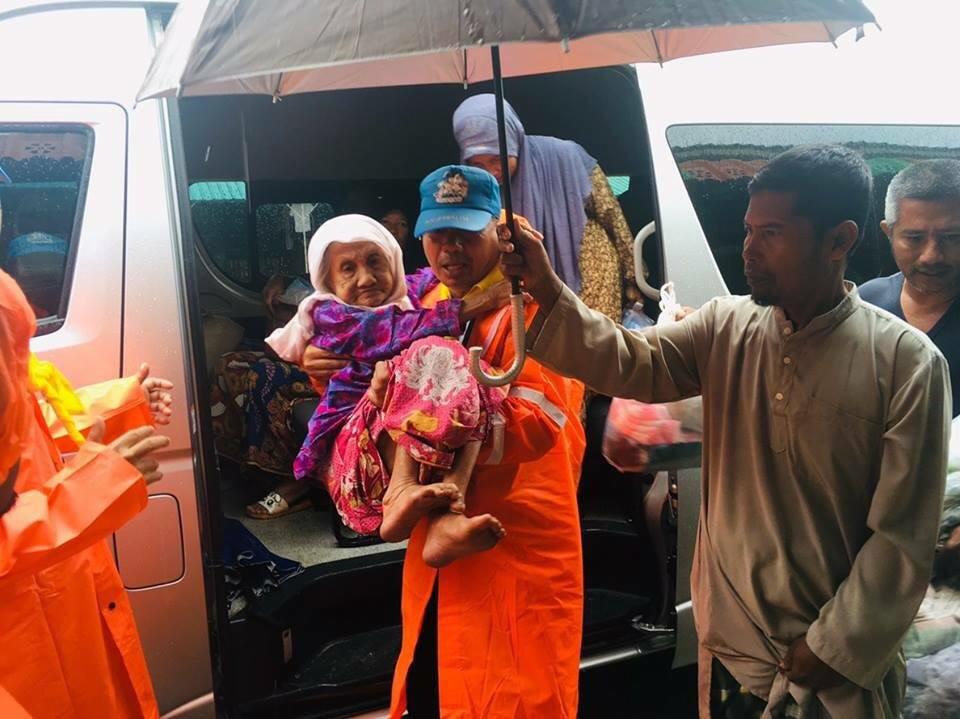  An elderly woman is carried to safety by a rescue worker in Nong Chik