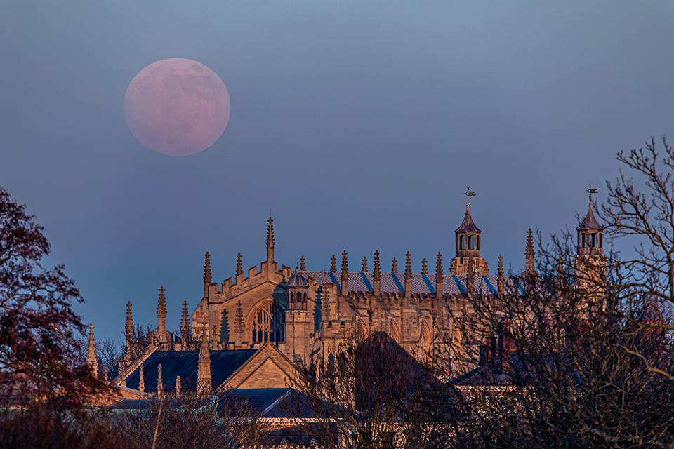  The reddish moon rises behind Windsor Castle in Berkshire