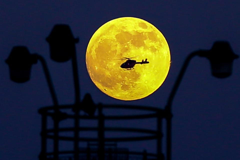  A helicopter flies in front of the Super Blood Wolf Moon over London