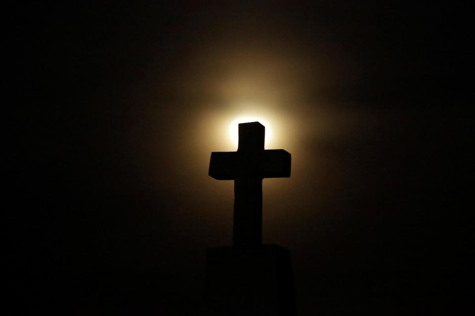  A cross headstone is silhouetted against the full moon ahead of a total lunar eclipse, known as the 'Super Blood Wolf Moon', at a cemetery in Ciudad Juarez, Mexico