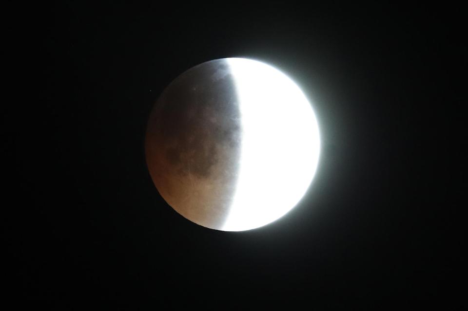  This mesmerising photo shows the earth's shadow begins to fall across the moon in Brighton