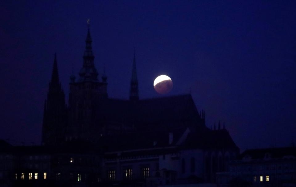  The red-tinged moon behind the Prague Castle during a lunar eclipse in Prague