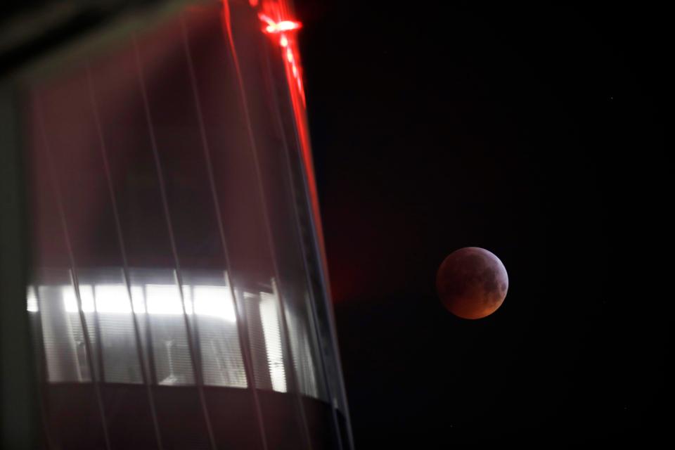  A full moon rises behind a skyscraper of the City Life neighborhood in Milan, Italy