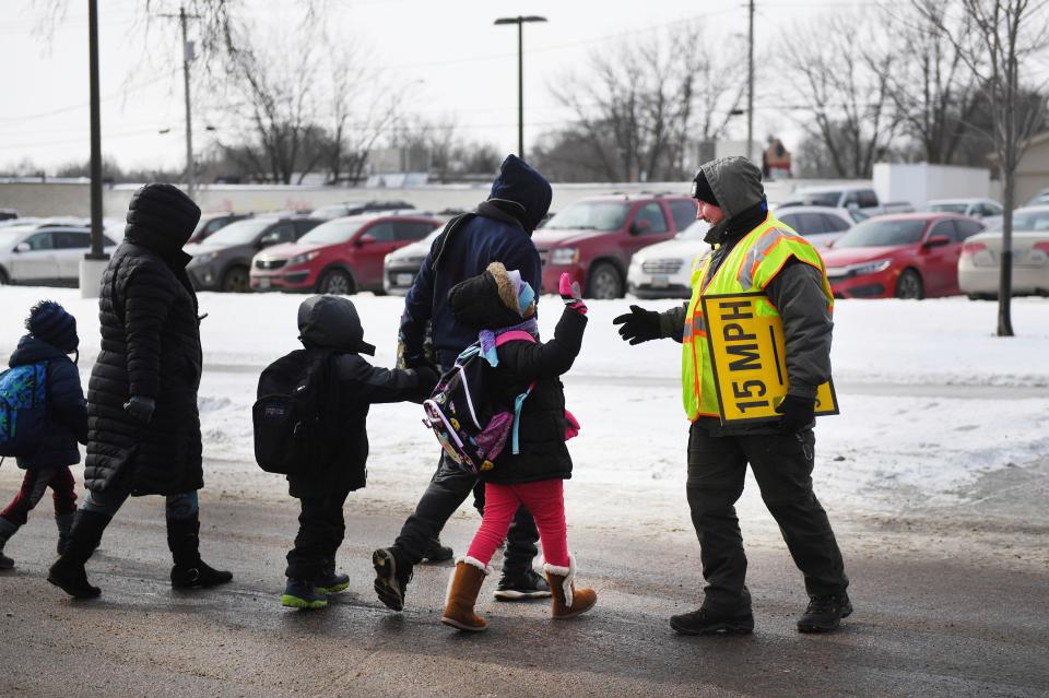  Students are helped to cross the road as they leave school early after heavy snow fell in Sioux Falls, South Dakota