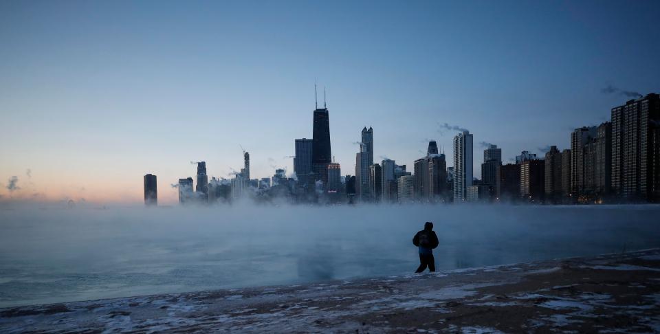  A man walks on North Avenue Beach as the sun rises over Lake Michigan in Chicago, Illinois