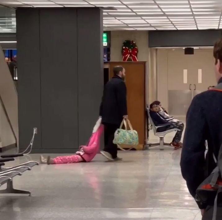  A fed up dad was spotted dragging his daughter through the airport