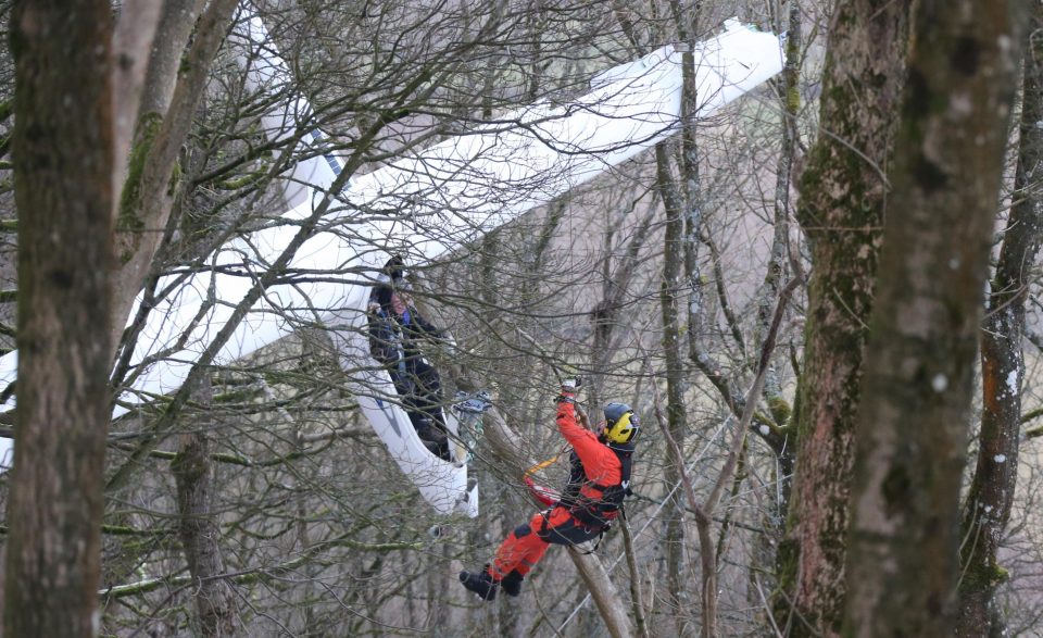  A rescuer gets close to the glider to carefully attach a winch to the pilot