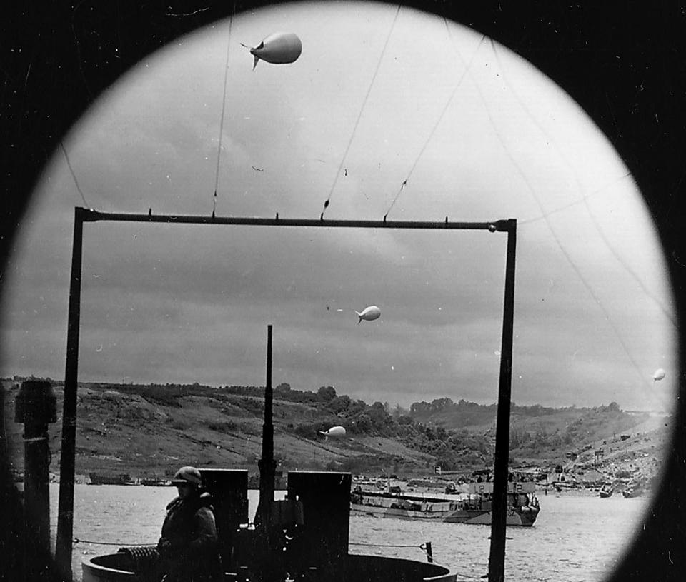  A rare view through porthole behind an anti-aircraft mount shows the assault on Normandy