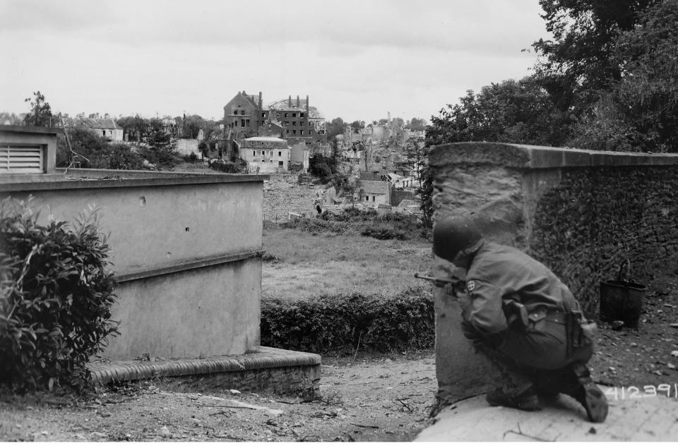  A soldier peers through the devastation, wary of enemy fire on the edge of a small French town