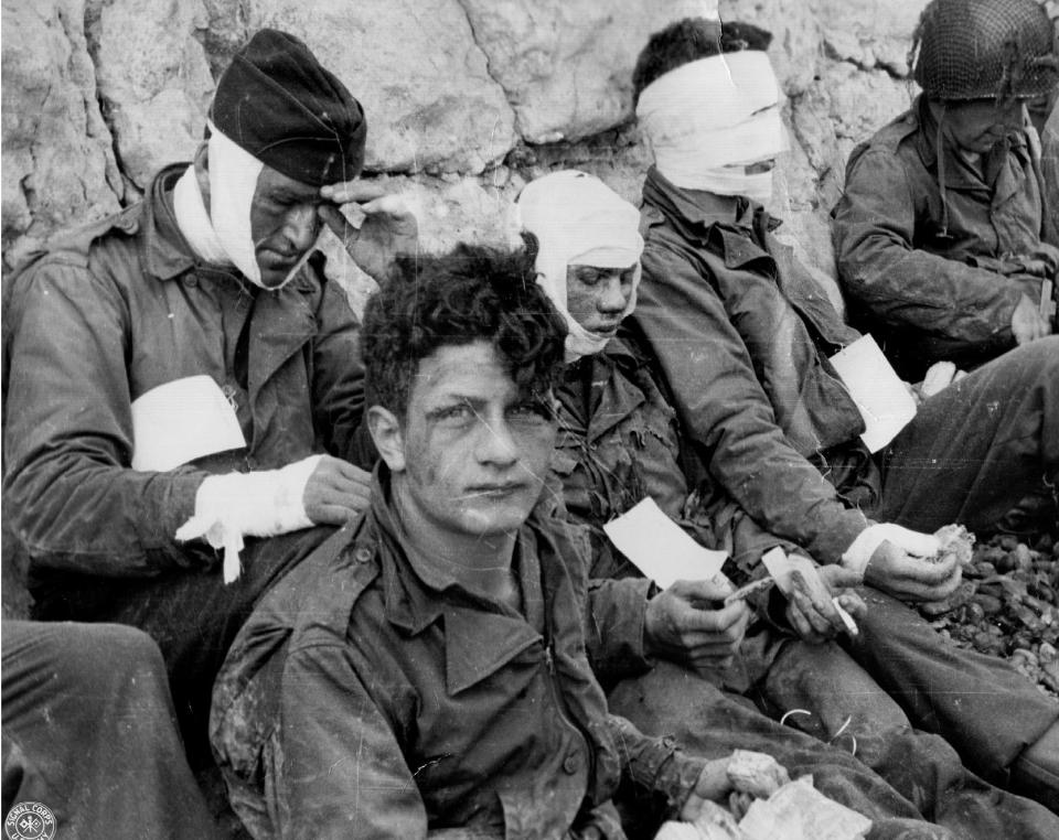  A group of American assault troops who stormed a beachhead gain the comparative safety offered by the chalk cliff