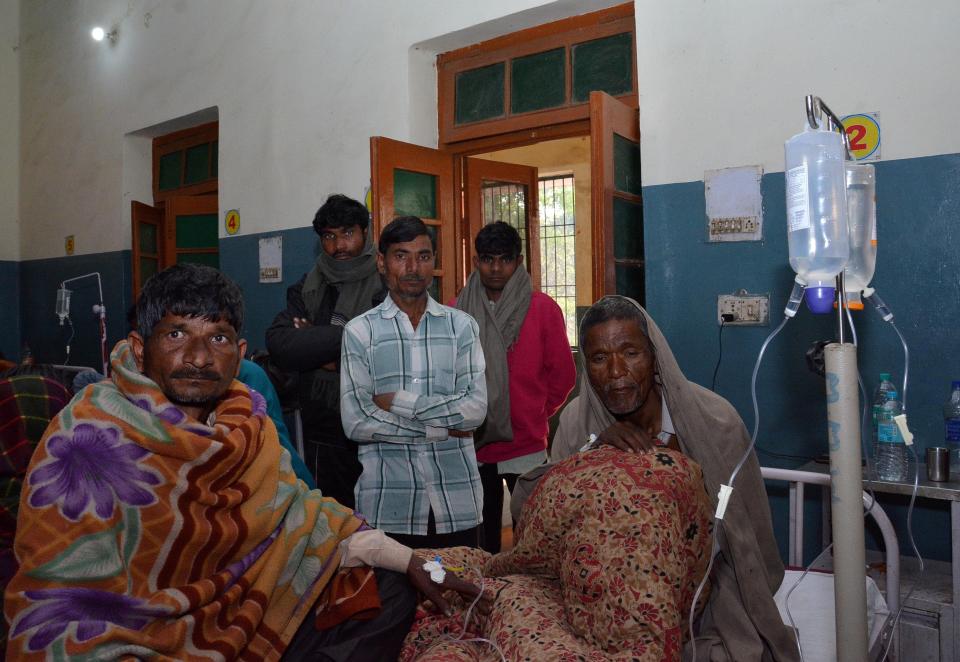  Two men who consumed bootleg alcohol sit on a hospital bed as relatives look on in Saharanpur. It's believed the bootleg alcohol was tainted with methanol