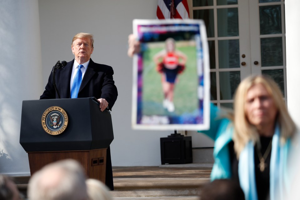  A mother lifts up a photograph of her son as Trump appears for the announcement