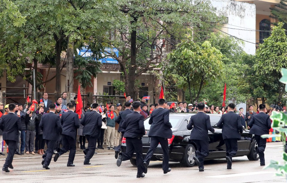 Suited and well-armed bodyguards follow the limo’s every turn