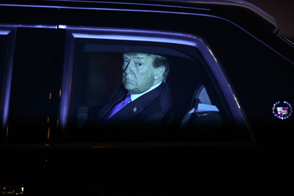 Trump peers out his diplomatic car as he leaves the airport