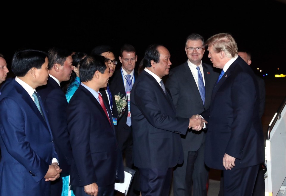 Trump shakes hands with dignitaries on the red carpet at Hanoi