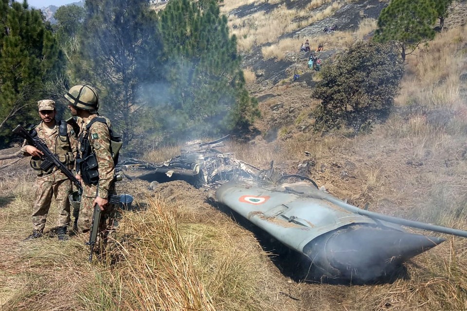 Pakistani soldiers stand next to what Pakistan says is the wreckage of an Indian fighter jet shot down in Pakistan controled Kashmir