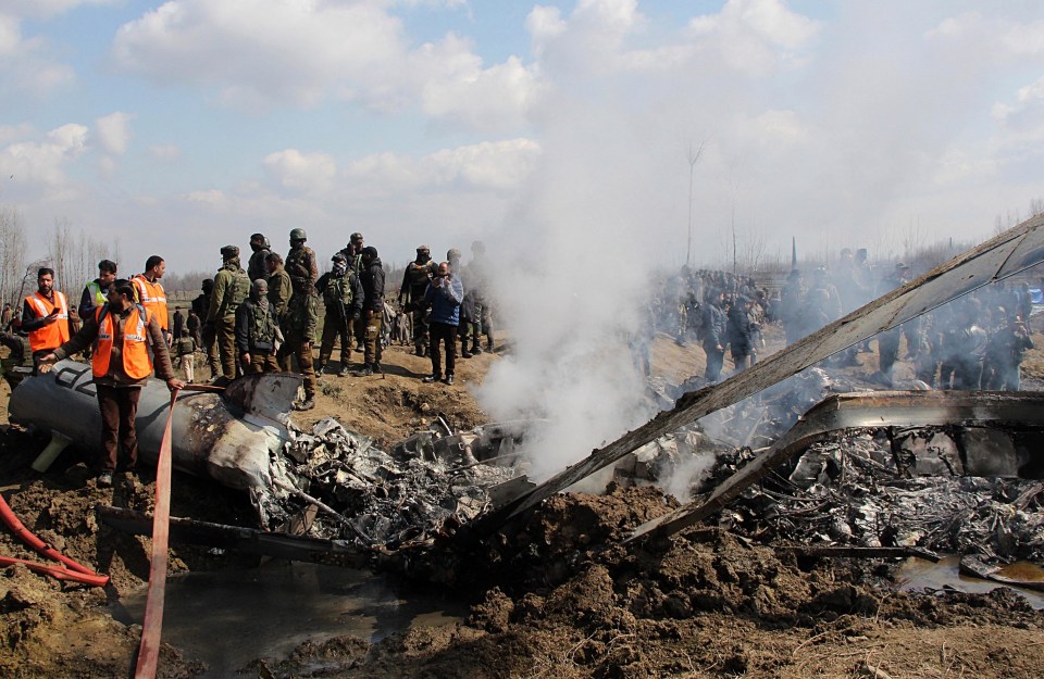 Fire and emergency members stand near the debris of the Indian military aircraft