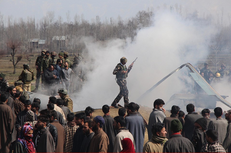 A soldier walks near the debris of the crashed Indian jet in Kashmir’s Budgam