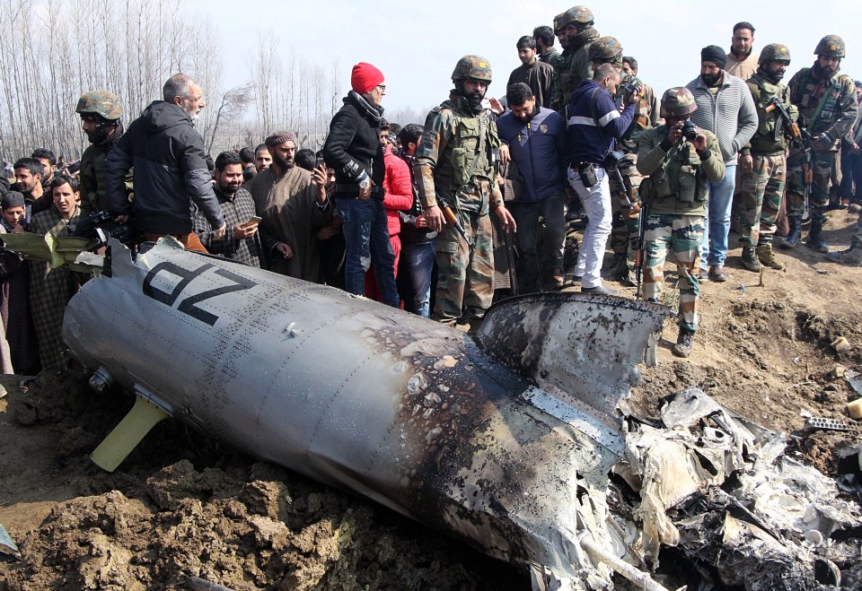 Members of the Indian army and locals stand near the remains of the Indian jet