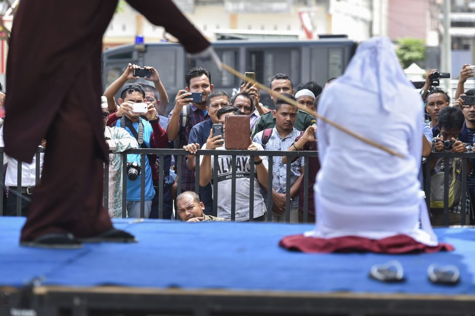 A woman is stuck with the cane while the crowd laps up it up, taking photos and video to watch later on