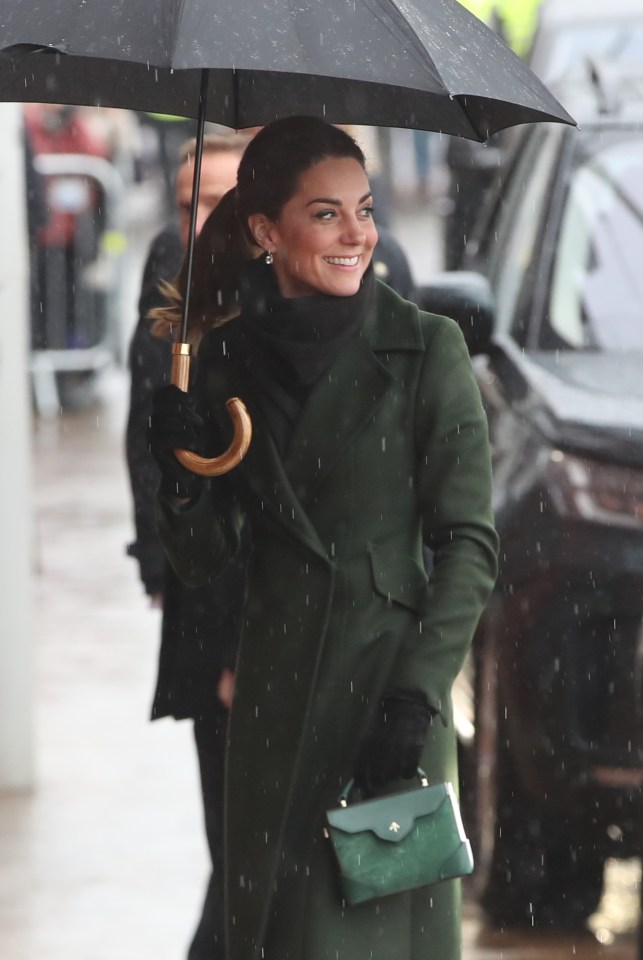 Kate Middleton beaming in the rain as she dons a coat and umbrella a la Mary Poppins