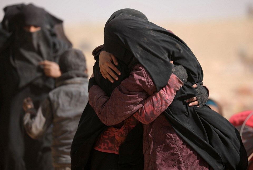 Women hug near the village of Baghouz